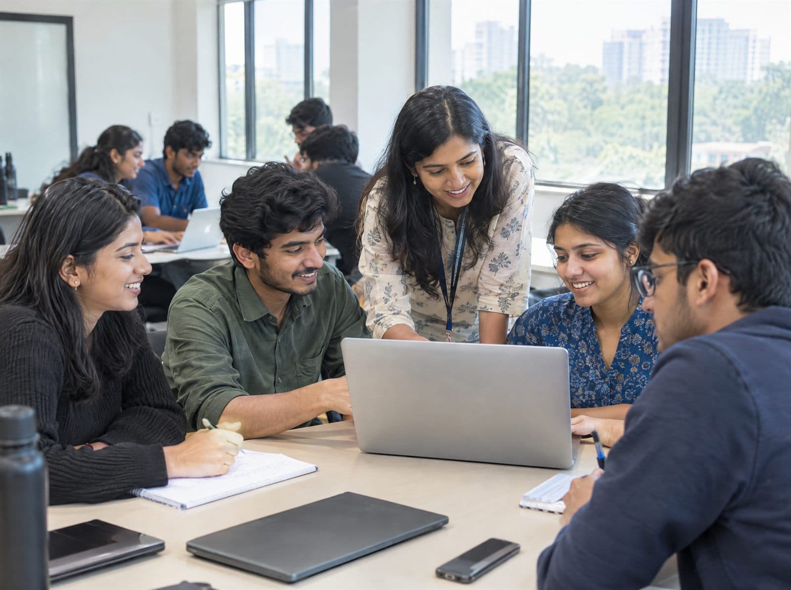 College students working together on laptops with a teacher guiding them in a bright classroom